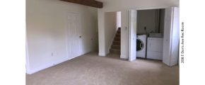 Carpeted rec room with exposed beam and laundry closet with side-by-side front load washer and top load dryer