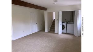 Carpeted rec room with exposed beam and laundry closet with side-by-side front load washer and top load dryer