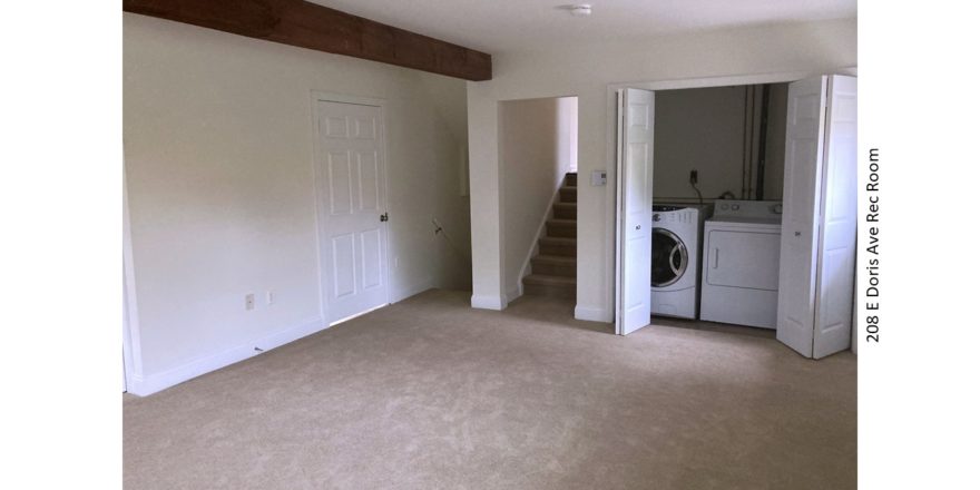 Carpeted rec room with exposed beam and laundry closet with side-by-side front load washer and top load dryer