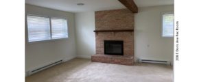 Carpeted rec room with exposed beam and brick fireplace with mantle