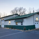 Side view of a white and dark green building with garages
