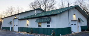 Side view of a white and dark green building with garages