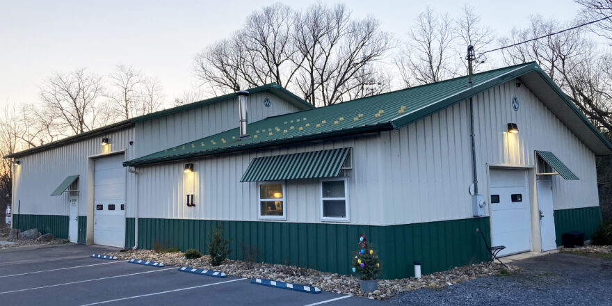 Side view of a white and dark green building with garages