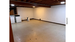 a large basement with white walls and wood beams on the ceiling and a washer and dryer unit