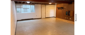 a large basement with white walls and wood beams on ceiling