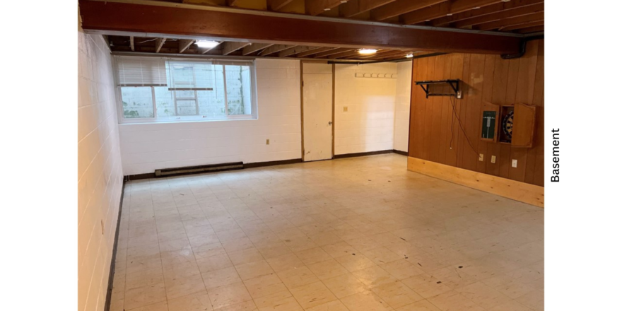 a large basement with white walls and wood beams on ceiling