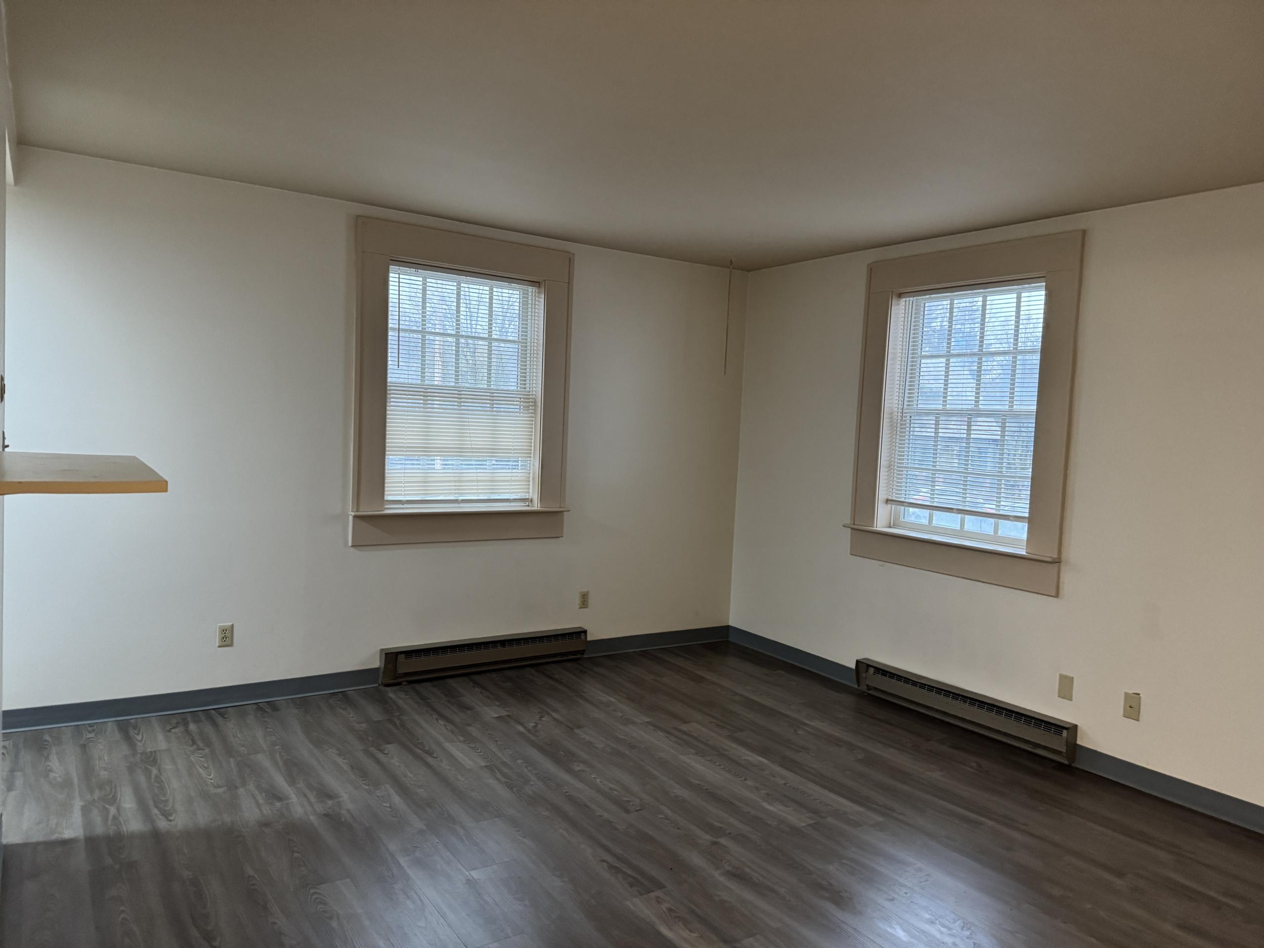 Empty room with hardwood floors and two windows