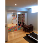 Multi-purpose space with shelving, kids table with chairs, and a treadmill