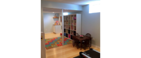 Multi-purpose space with shelving, kids table with chairs, and a treadmill