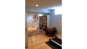 Multi-purpose space with shelving, kids table with chairs, and a treadmill