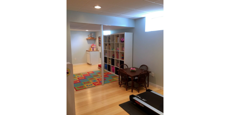 Multi-purpose space with shelving, kids table with chairs, and a treadmill