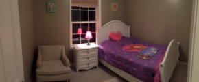 Carpeted bedroom with full-size bed, armchair, and small dresser with lamp