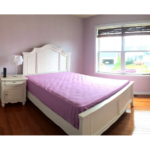 Bedroom with hardwood floor and full size bed, nightstand with lamp, and small chair
