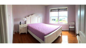 Bedroom with hardwood floor and full size bed, nightstand with lamp, and small chair