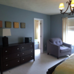 Carpeted bedroom with armchair and dresser and chandelier
