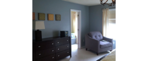 Carpeted bedroom with armchair and dresser and chandelier