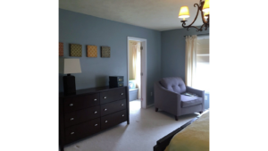 Carpeted bedroom with armchair and dresser and chandelier