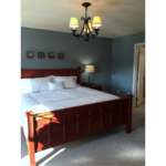 Carpeted bedroom with large bed, chandelier, and attached bathroom