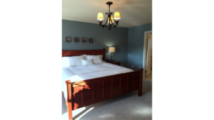 Carpeted bedroom with large bed, chandelier, and attached bathroom