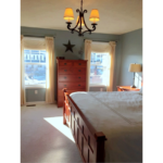 Furnished, carpeted bedroom with small chandelier lighting