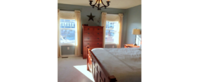 Furnished, carpeted bedroom with small chandelier lighting