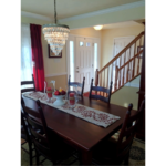 Entryway with wooden staircase and dining room with large table and chandelier