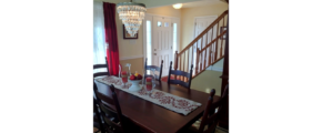 Entryway with wooden staircase and dining room with large table and chandelier