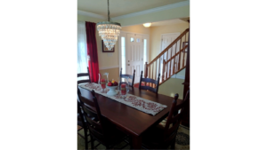 Entryway with wooden staircase and dining room with large table and chandelier