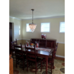 Furnished dining room with hardwood floors, area rug, and chandelier