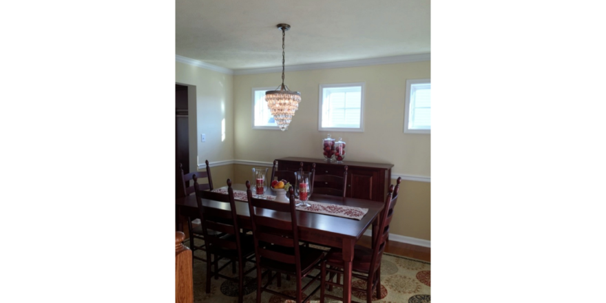 Furnished dining room with hardwood floors, area rug, and chandelier