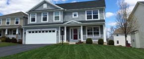 Exterior of two story house with gray siding, large yard, driveway, and front porch