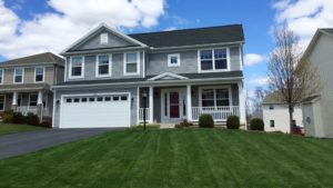 Exterior of two story house with gray siding, large yard, driveway, and front porch