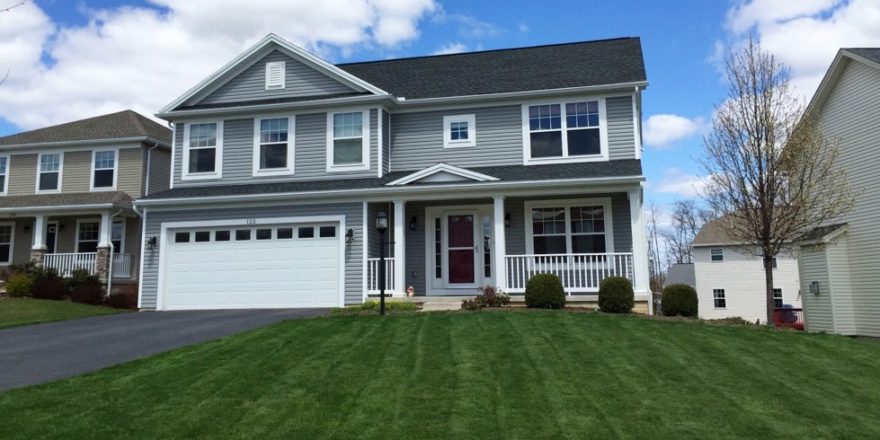 Exterior of two story house with gray siding, large yard, driveway, and front porch