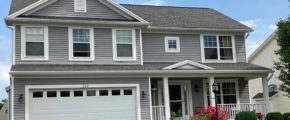 Exterior of two story house with gray siding, large yard, driveway, and front porch