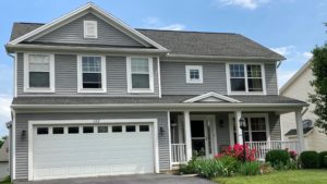 Exterior of two story house with gray siding, large yard, driveway, and front porch