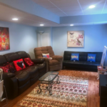 Furnished family room with over-stuff chairs, hardwood floors, and area rug