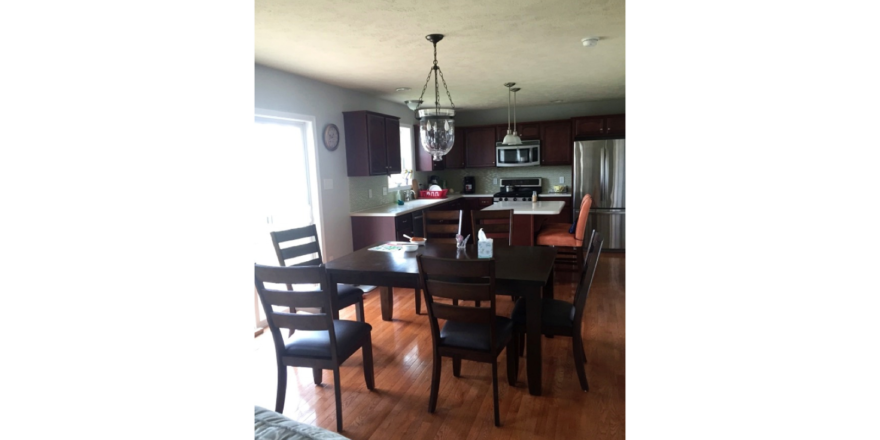 Kitchen with stainless steel appliances, large table and island with seating