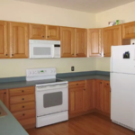 Kitchen with wood-tone cabinets, double bowl sink and white appliances