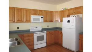 Kitchen with wood-tone cabinets, double bowl sink and white appliances