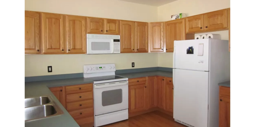 Kitchen with wood-tone cabinets, double bowl sink and white appliances