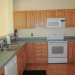 Kitchen with wood-tone cabinets, double bowl sink and white appliances