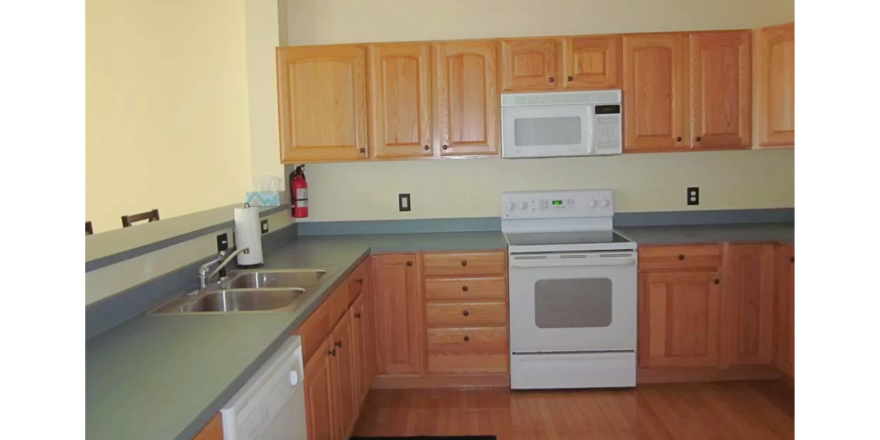 Kitchen with wood-tone cabinets, double bowl sink and white appliances