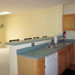 Kitchen and dining area with wood-tone cabinets, double bowl sink, dishwasher, and bar stool seating