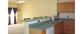 Kitchen and dining area with wood-tone cabinets, double bowl sink, dishwasher, and bar stool seating