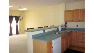 Kitchen and dining area with wood-tone cabinets, double bowl sink, dishwasher, and bar stool seating