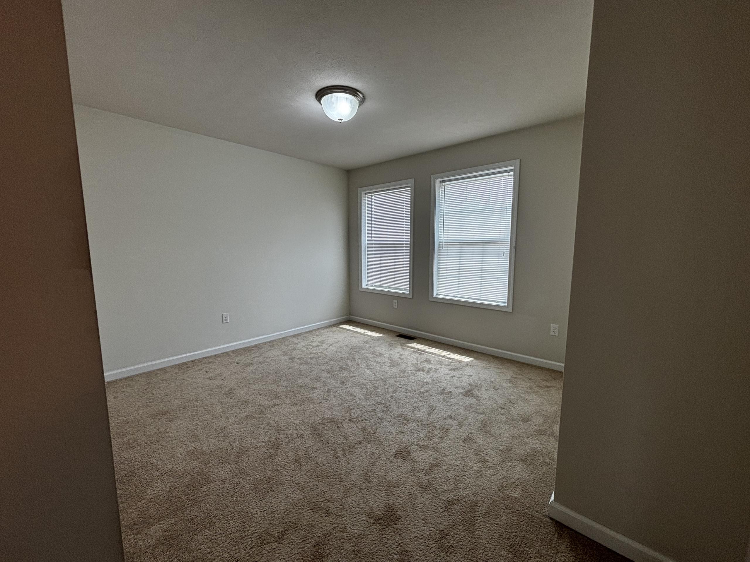 Empty bedroom with carpet and two windows