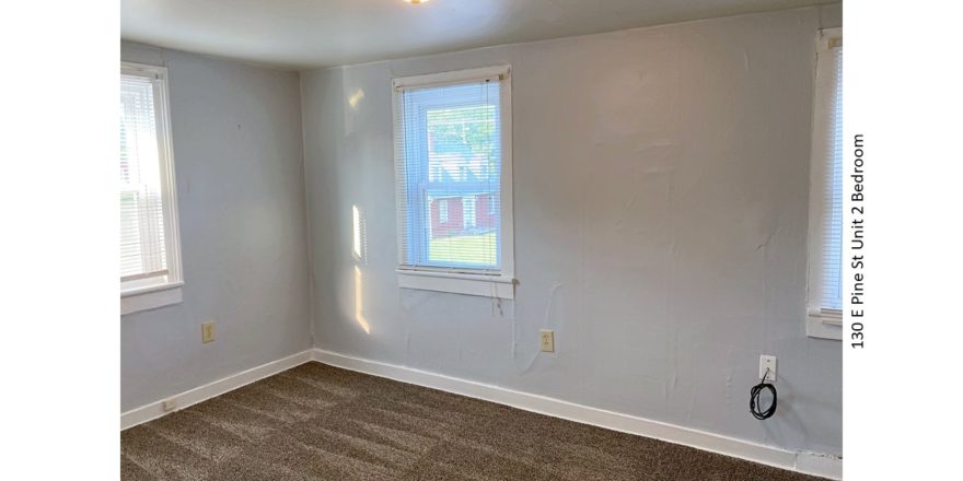 Unfurnished, carpeted bedroom with two windows