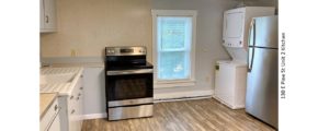 Kitchen with window, pale blue counters, wood-style flooring, stainless steel range oven and refrigerator and white stackable washer/dryer