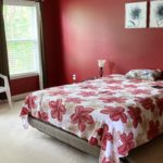 Carpeted bedroom with large bed, side tables and chair