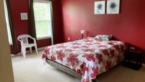 Carpeted bedroom with large bed, side tables and chair